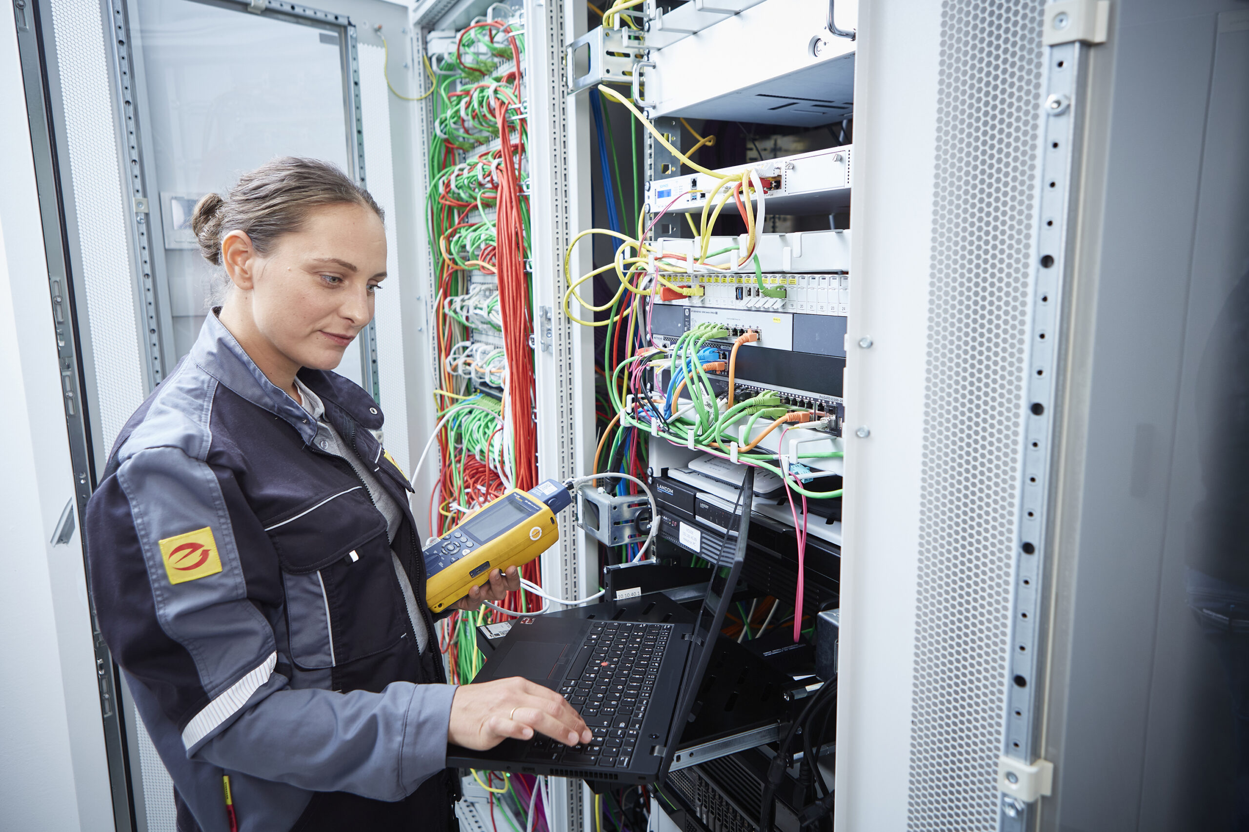 E-Handwerkerin führt Messung an Datenschrank durch